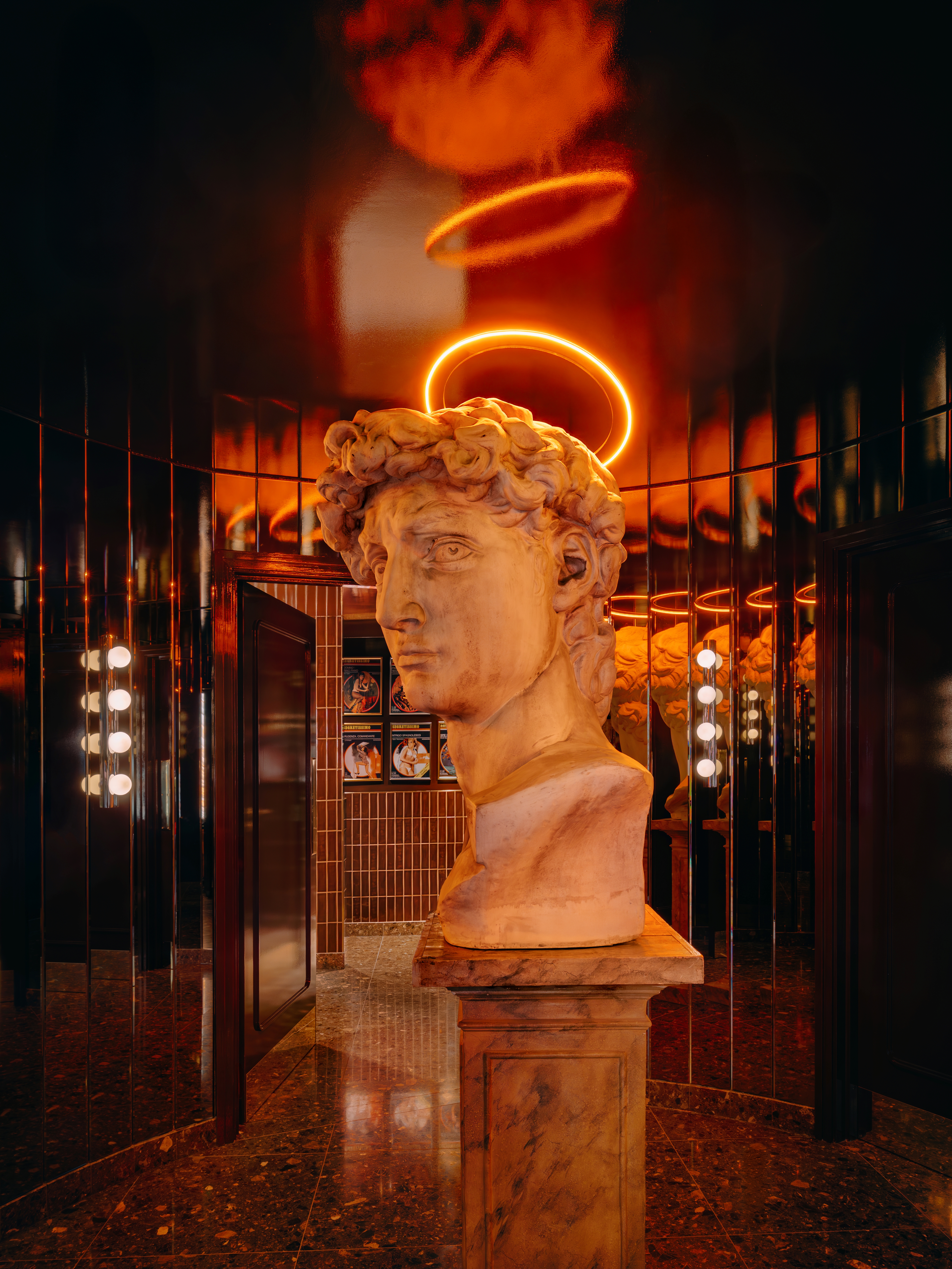A massive bust of David inside a red-tinted chrome bathroom
