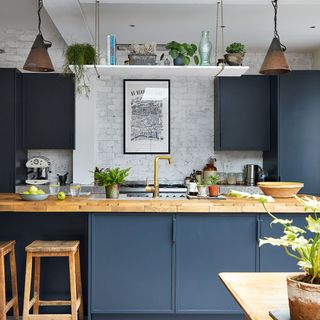 Blue kitchen with wooden work surface and shelf hung from the ceiling