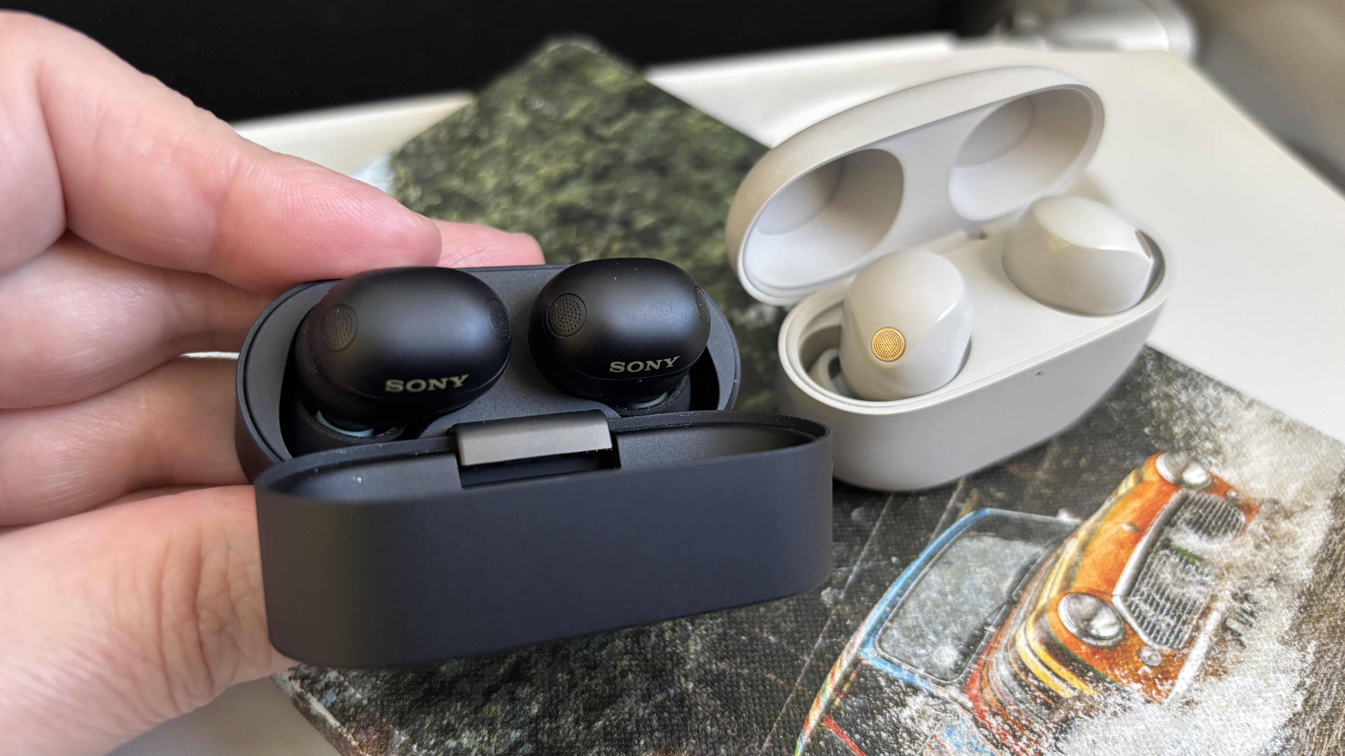Sony WF-100XM6 and XM5 wireless earbuds with open cases in black and platinum silver finishes