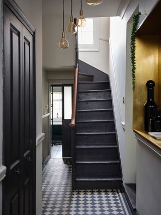 Black painted staircase in hallway with checkerboard flooring