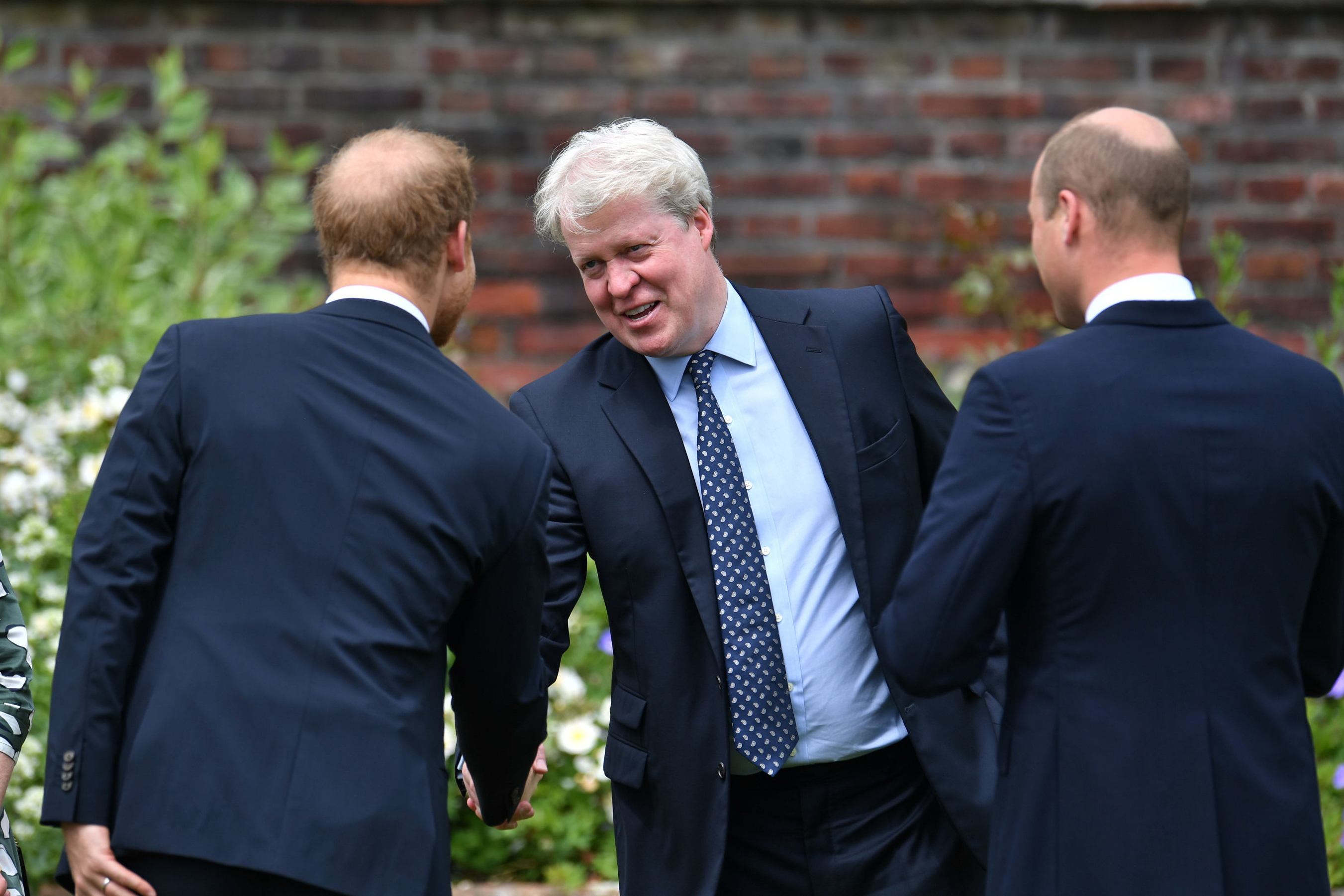 Prince Harry shaking hands with Earl Spencer next to Prince William