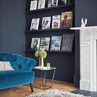 dark blue living room with picture wall creating using picture ledges painted to match the walls