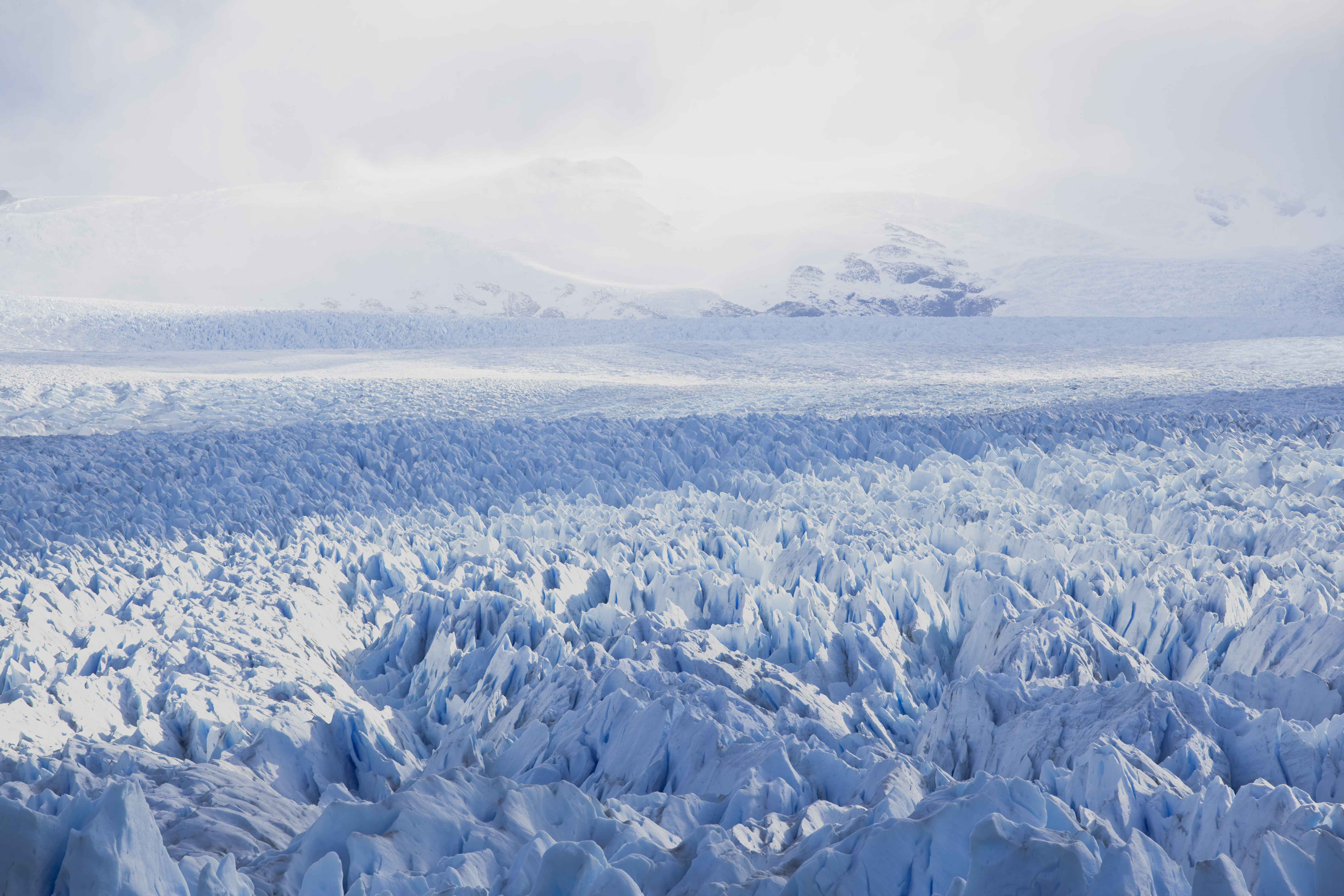 icy landscape showing a glacier and white mountains in the background