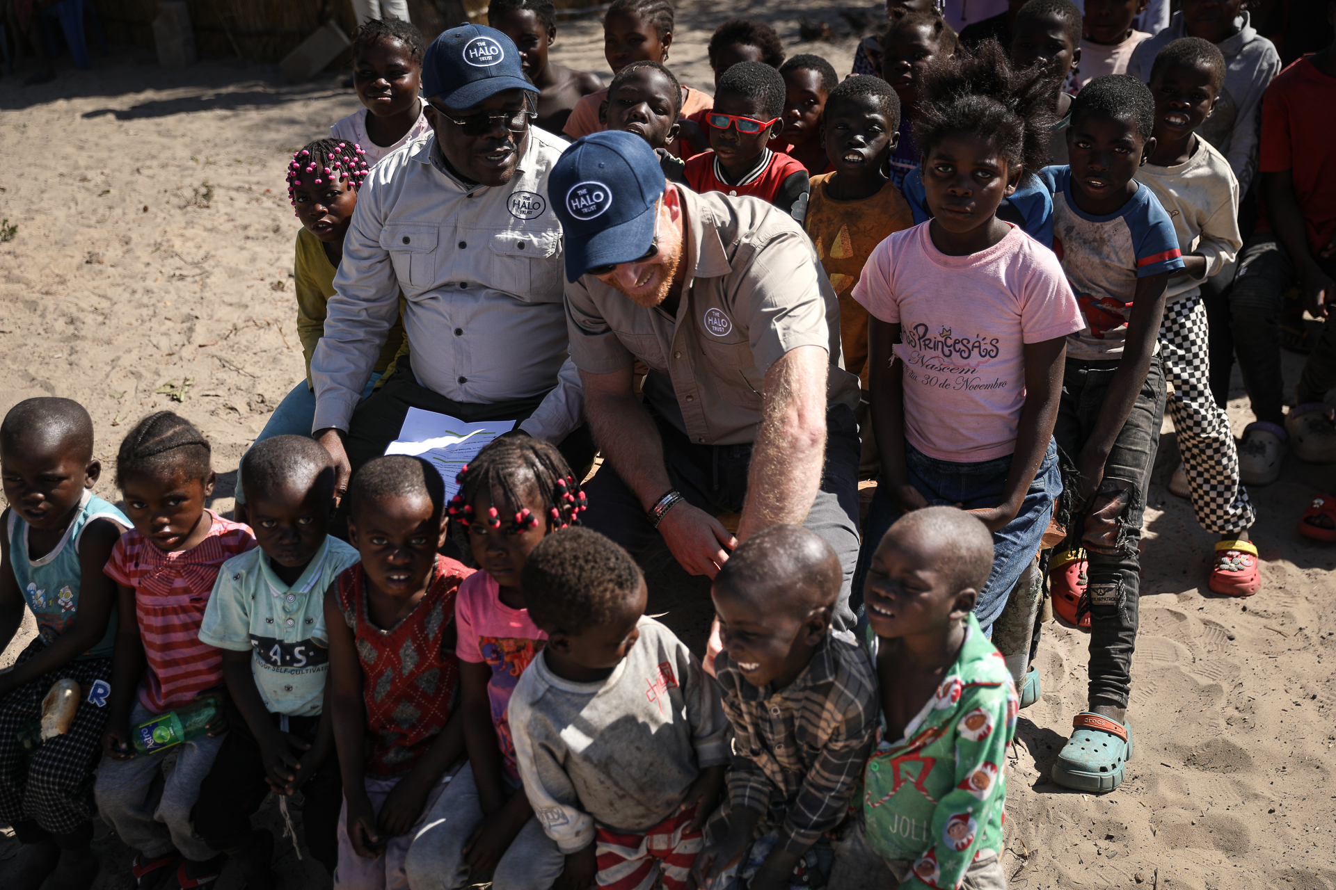 Prince Harry sitting with a group of children in Angola