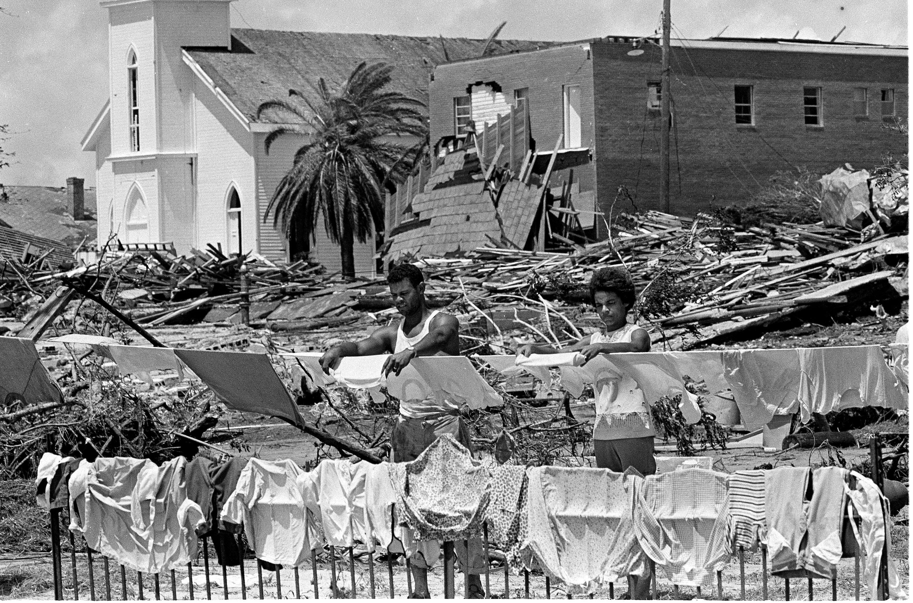 2NGBGYK Anthony Piernas helps Linda Porter hang her laundry in Pass Christian, Miss., Aug. 20, 1969, two days after Hurricane Camille heavily damaged the church and apartment house in the background. (AP Photo/Jack Thornell)