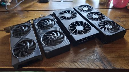 Four budget graphics cards lined up in a row on a wooden desk