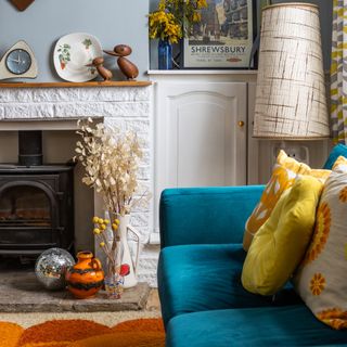 A living room with a wood burning stove in place of a fireplace with a patterned rug in front of it