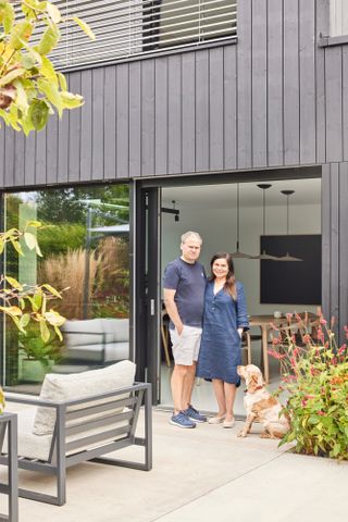 A couple and their dog stand outside their modern self build home