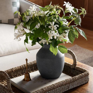 A dark gray vase on a table with white flowers.