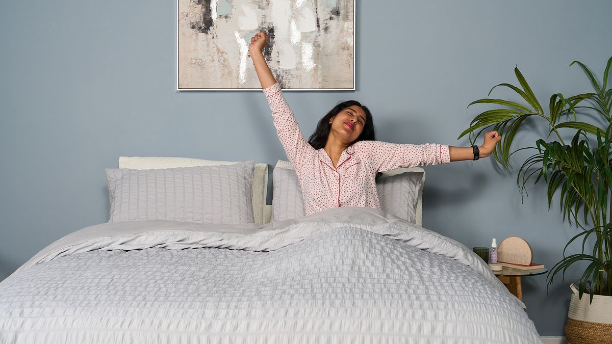 Tester Becky George wakes up smiling, her arms outstretched, after a great night's sleep on the Saatva Classic mattress