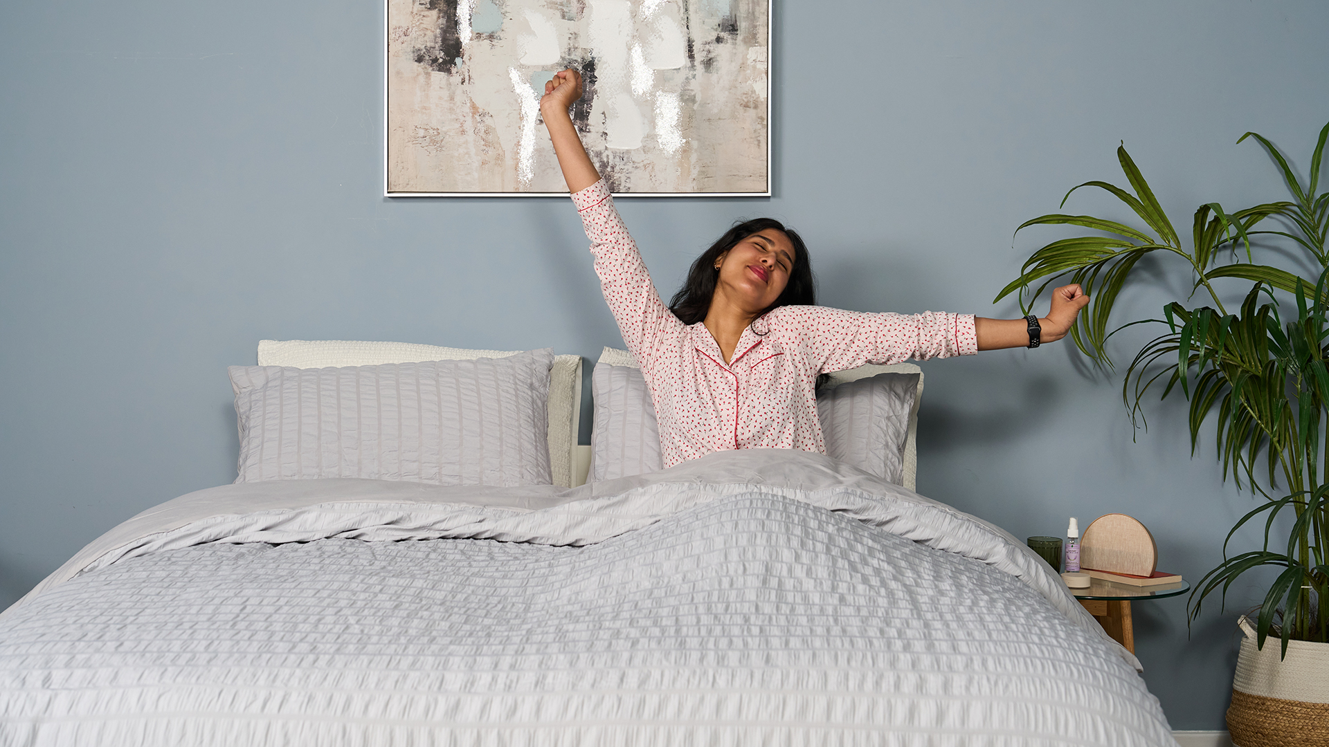 Tester Becky George wakes up smiling, her arms outstretched, after a great night's sleep on the Saatva Classic mattress