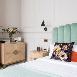 Wall panelling in bedroom, teal scalloped upholstered headboard, bedside table and chest of drawers