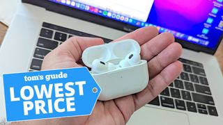 AirPods Pro 2 held in hand with MacBook Pro in background