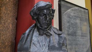 A picture of the bust of French scholar and philologist Jean-François Champollion sat in front of a replica of the Rosetta Stone