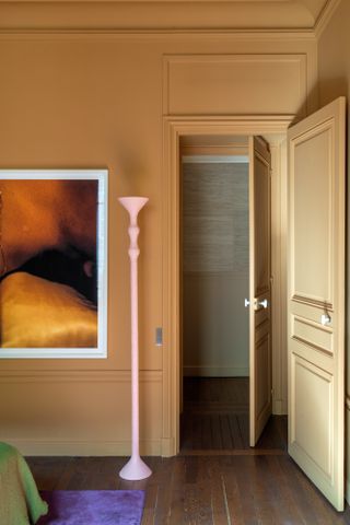 Bedroom with warm beige walls and pale pink floor lamp