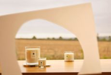 Jo Malone London scented candles on a table outdoors, seen through a cut-out