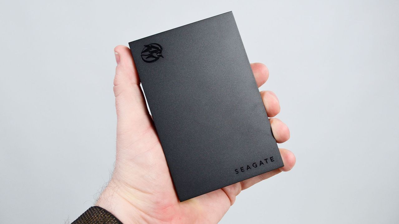 A masculine hand holding a Seagate FireCuda external gaming hard drive