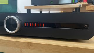 Front angled shot showing front panel volume LED display on Roksan Atessa Streaming Amplifier on wooden rack