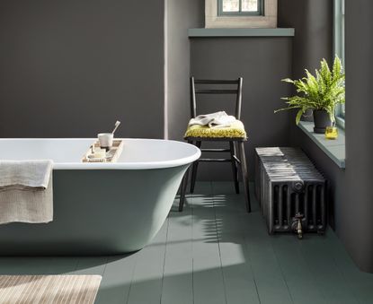 A bathroom with a free-standing bath painted in two shades of green