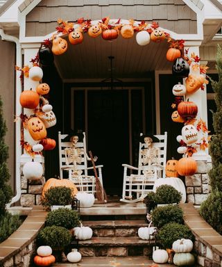 Halloween outdoor decor idea by Felicia Hausman using pumpkins as a garland and two skeletons sitting on white chairs