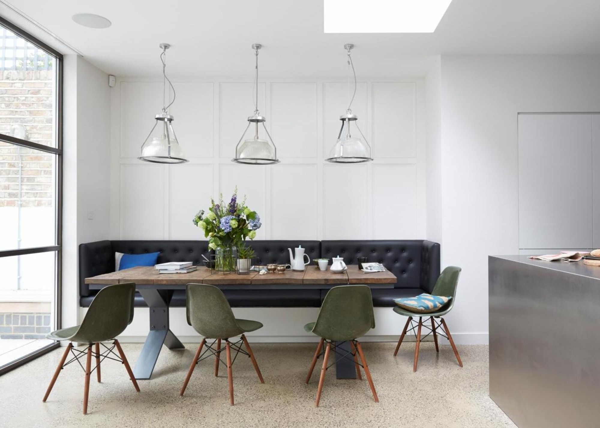Dining area with banquette seating, a table with inset legs and Eames dining chairs