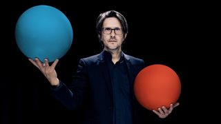 A press photo of Steven Wilson holding a blue sphere in his right hand and a red sphere in his left, provided for the release of his 2025 album The Overview.