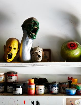 sculptures of contorted faces by Ashley Bickerton on a shelf