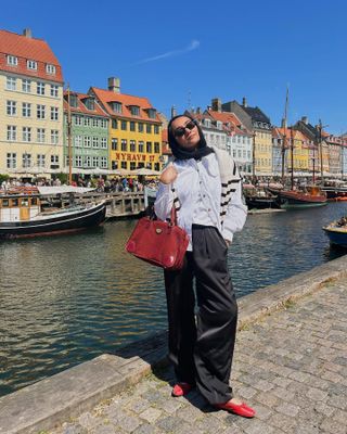 Yusra Siddiqui vestindo calças de seda preta e sapatilhas vermelhas em Copenhague