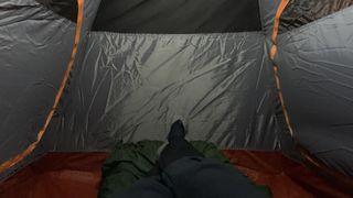 The interior of a Forclaz MT500 tent, showing the bathtub floor of the tent and the feet and legs of a person lying inside