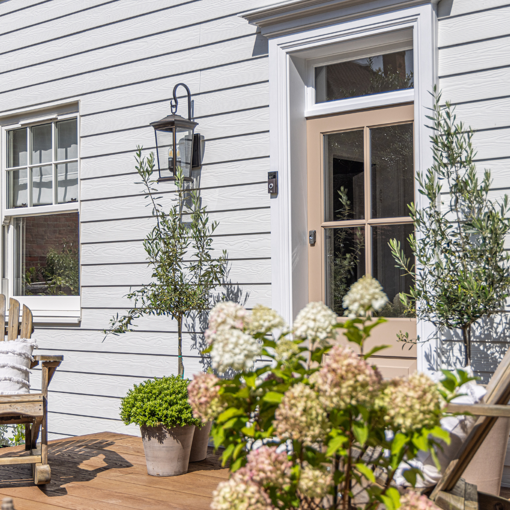small front porch ideas, white front porch with shiplap, decking, plants, wooden rocking chair, lanterns