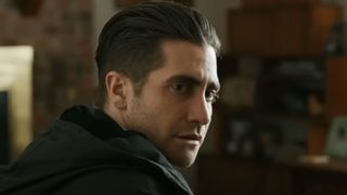 Jake Gyllenhaal as Detective Loki in Prisoners, sitting in a kitchen with a worried expression on his face.