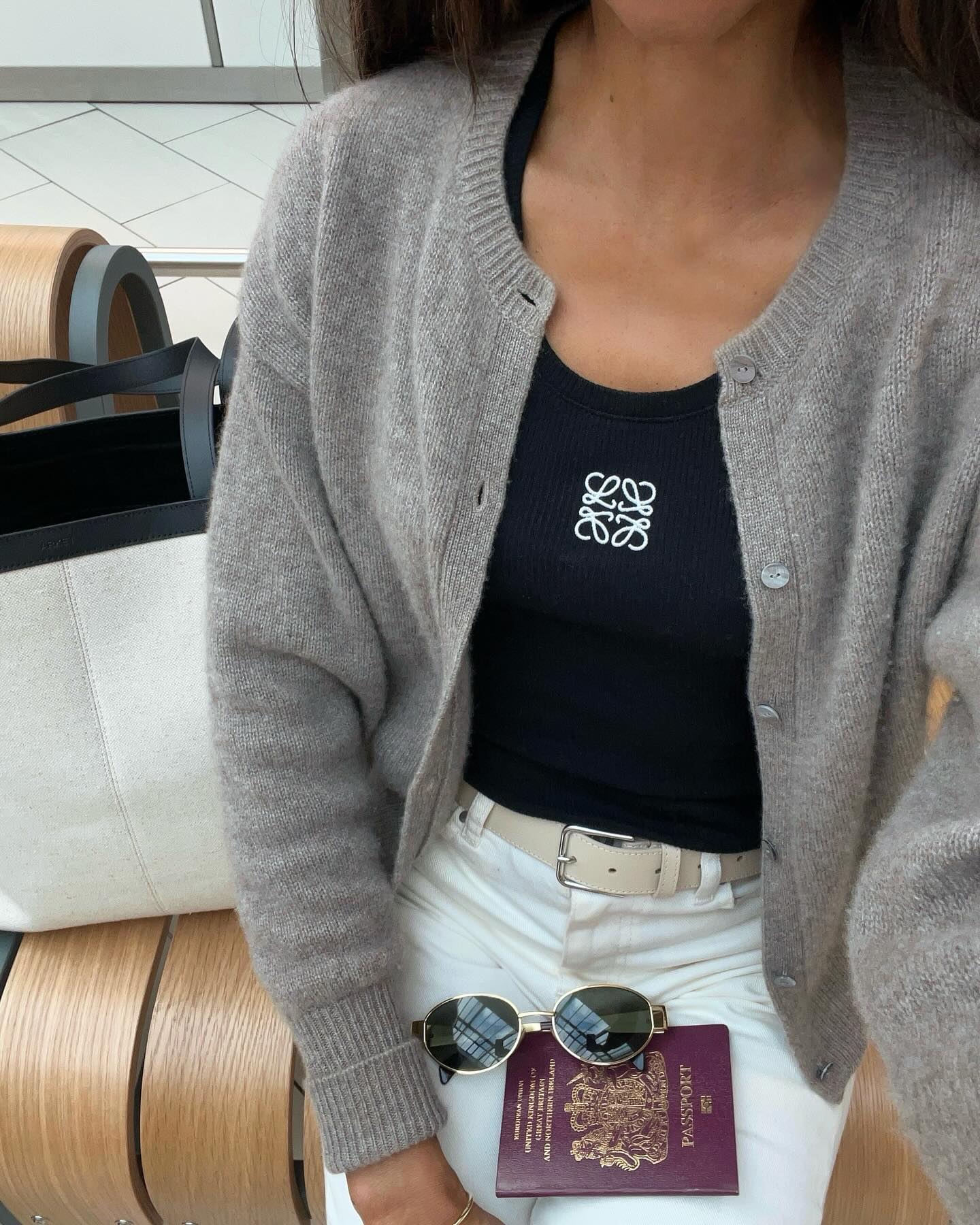 @symphonyofsilk wears a pair of white jeans, a black top and a grey cardigan whilst at the airport