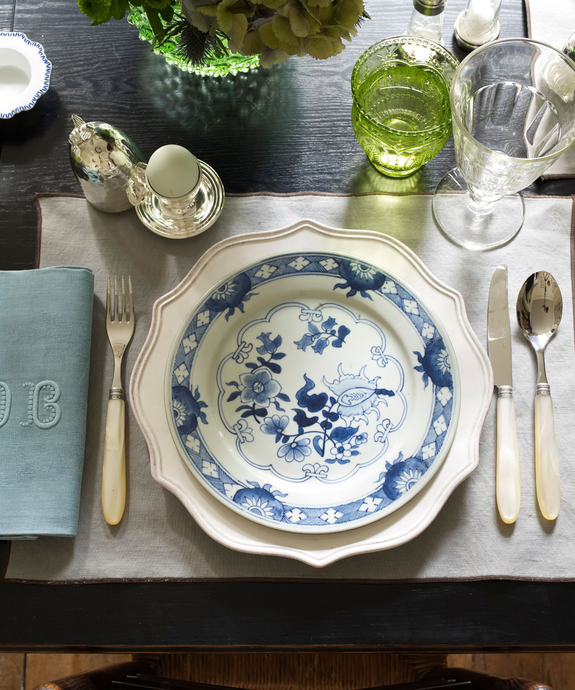 Place setting with blue and white plate, mother-of-pearl handled cutlery and a monogrammed napkin