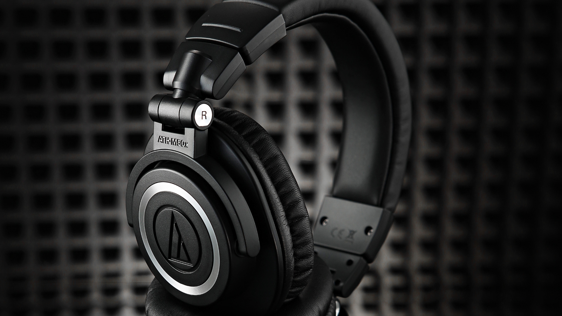 A pair of Audio-Technica ATH-M50x headphones in a recording studio