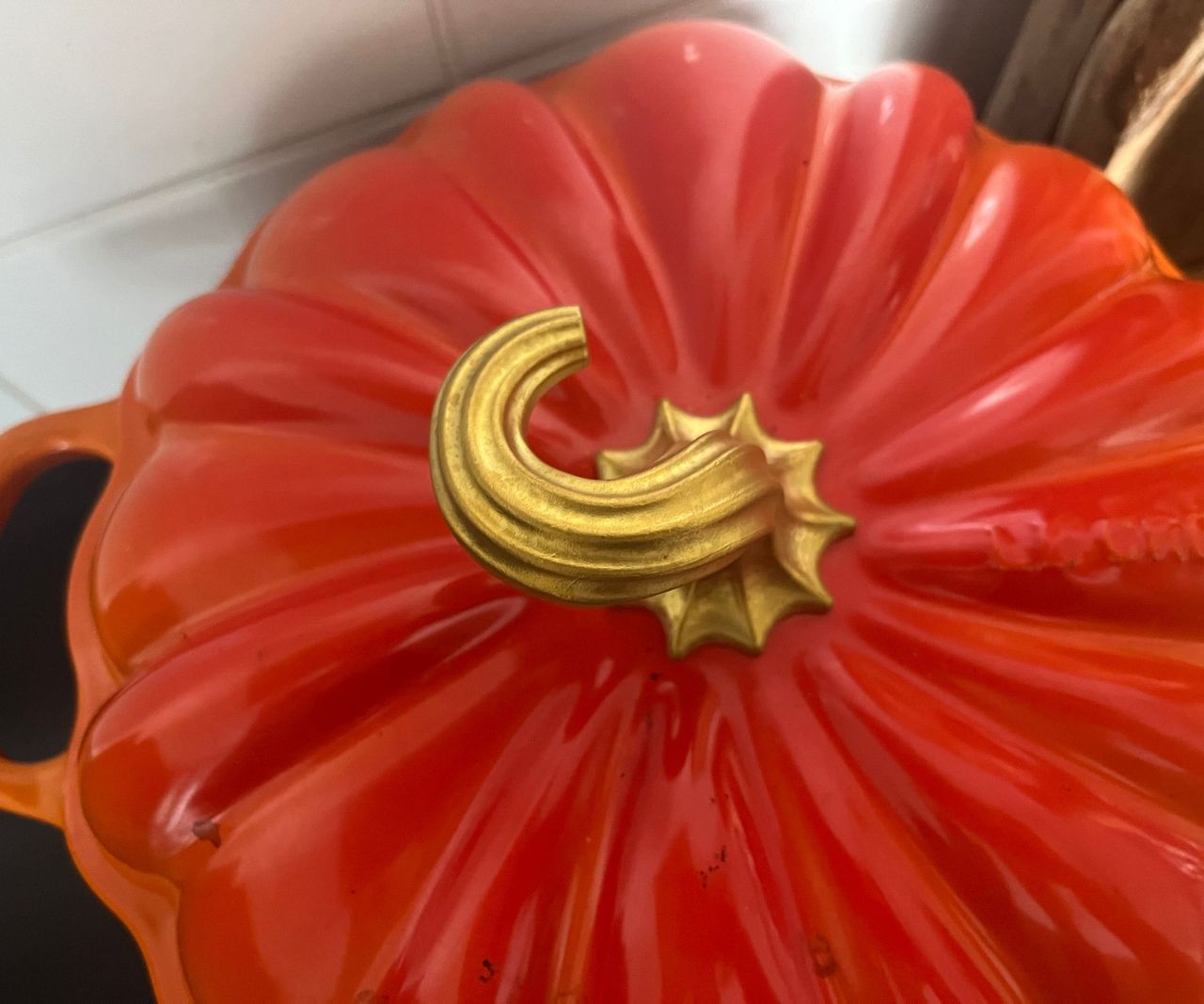 An orange Le Creuset pumpkin Cocotte on a black kitchen stove top