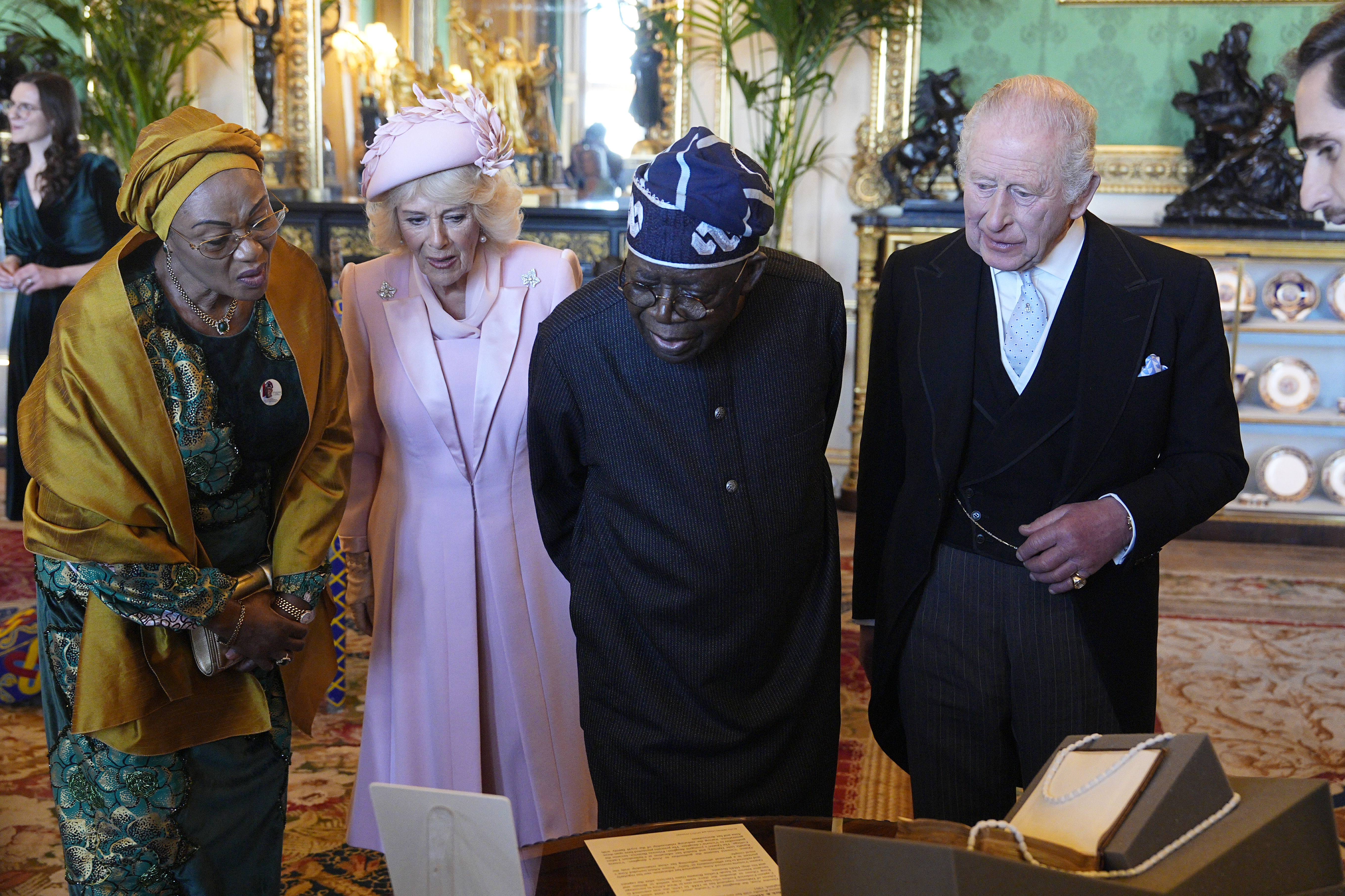 Queen Camilla, King Charles and the First Lady and President of Nigeria examining objects from the Royal Collection