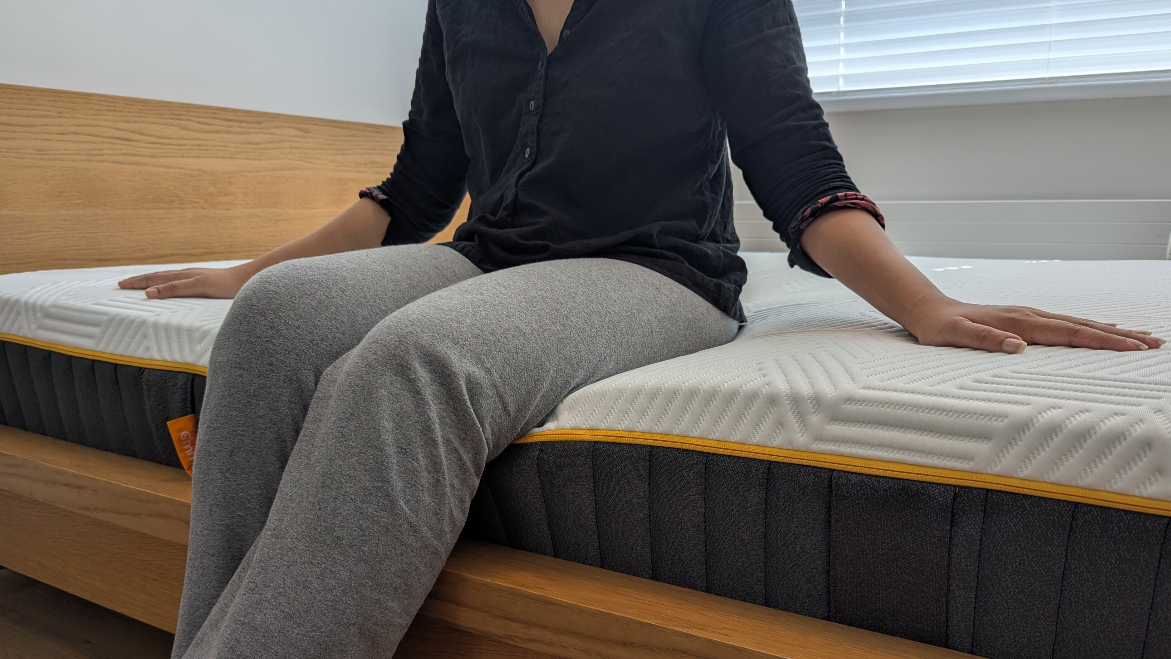 Person sitting on the edge of the Emma Hybrid Airgrid mattress