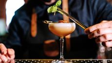 A bartender garnishes a cocktail