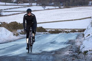 Rider cycling up a snowy lane wearing Lake 146 boots