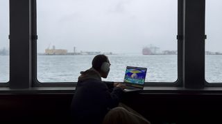 Someone uses MacBook Pro against backdrop of the ocean