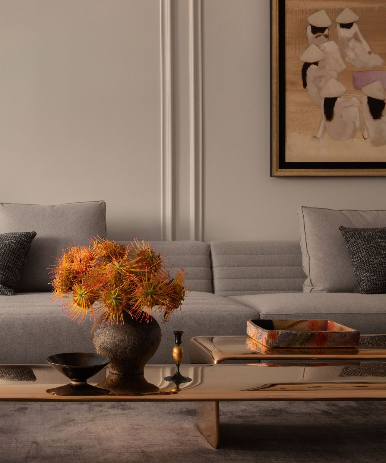 A neutral living room with wall molding, a shiny coffee table, and a large, gray sofa