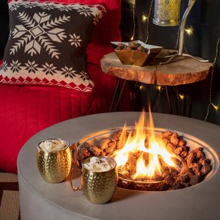 outdoor firepit with gold mugs of hot chocolate and marshmallows