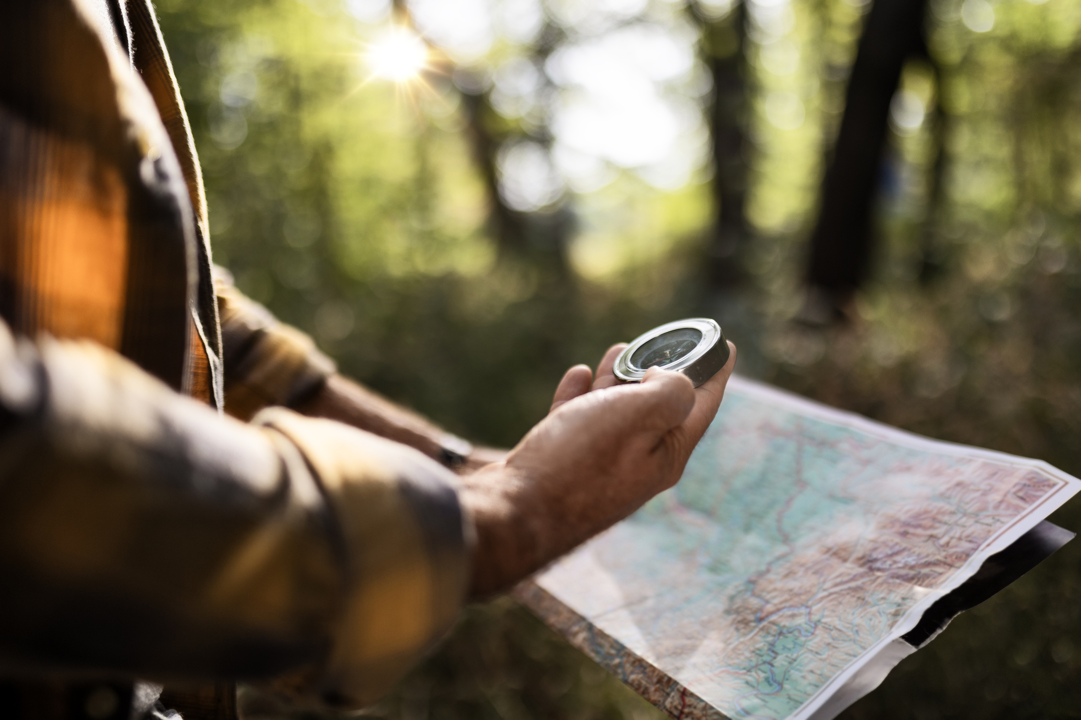 Mature Man Hiking Through Autumn Woods Using Map And Compass Navigating.