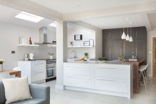 a white and modern kitchen with dark units at the back, one of our favorite open plan kitchen ideas