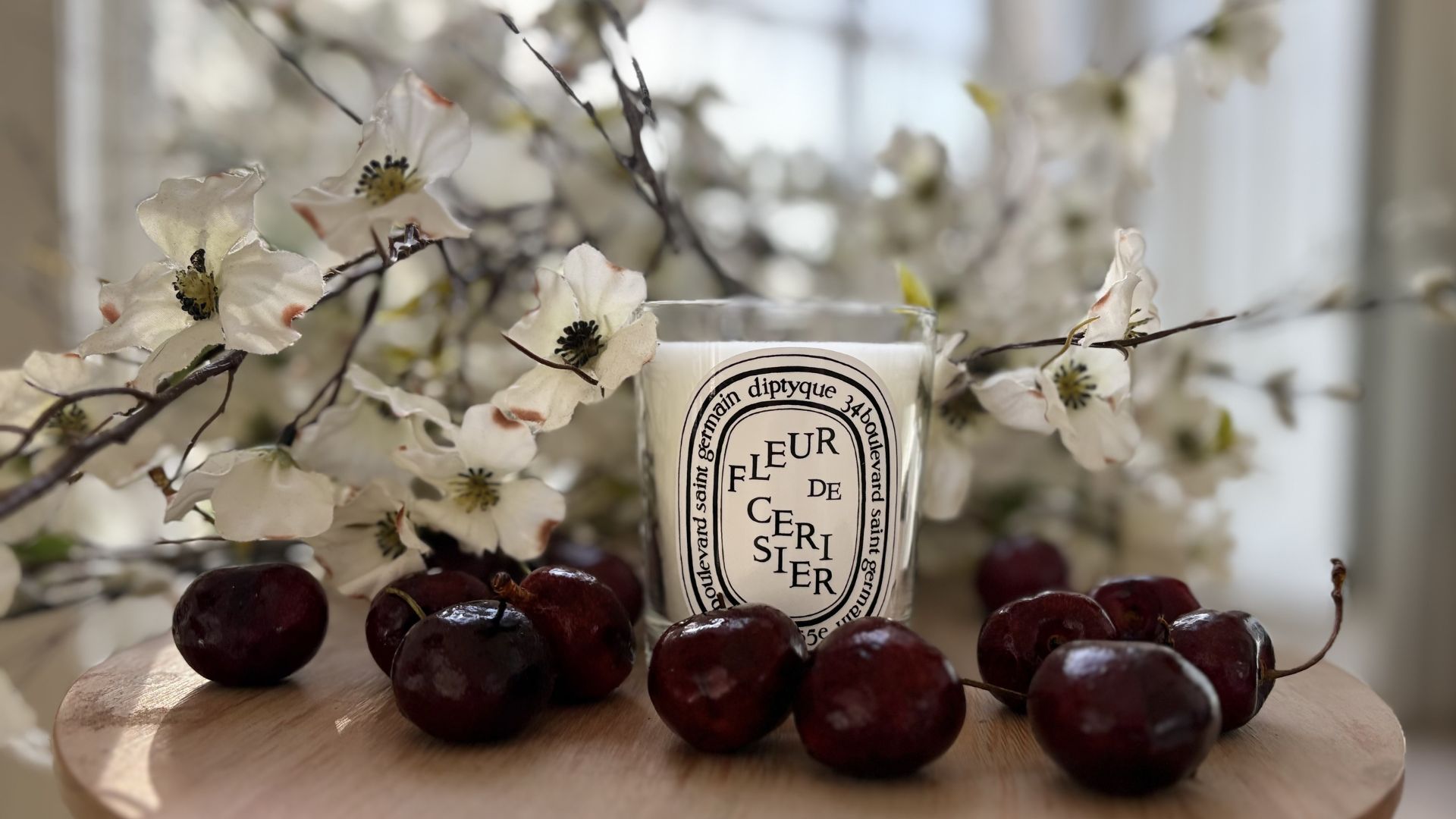 Diptyque Fleur de Cerisier Candle with cherries and blossom around it