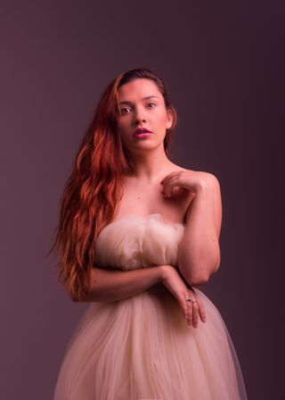 A portrait of a female in a pink dress, looking at the camera