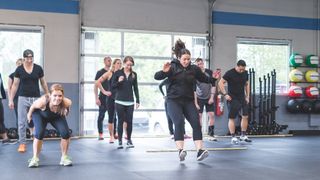 Women in an exercise class perform broad jumps