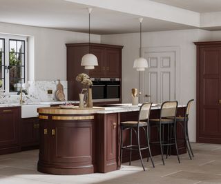 A burgundy and marble kitchen with extra storage added to the island with a curved detail