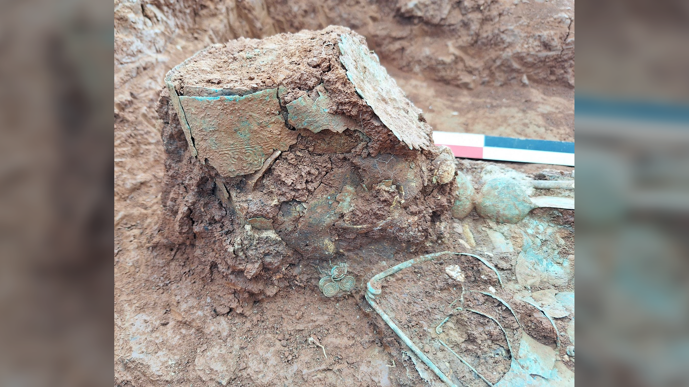 a partially excavated human skeleton with a greenish bronze crown around the skull
