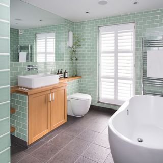 bathroom with mint colour tile wall bathtub window and wash basin